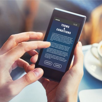 photograph of a person holding a mobile phone reading terms and conditions